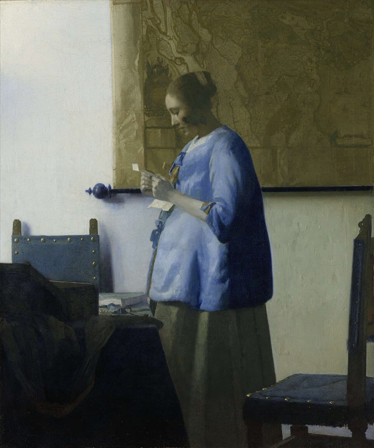 Vermeer's Woman Reading a Letter, showing a woman in blue reading privately by a map-covered wall